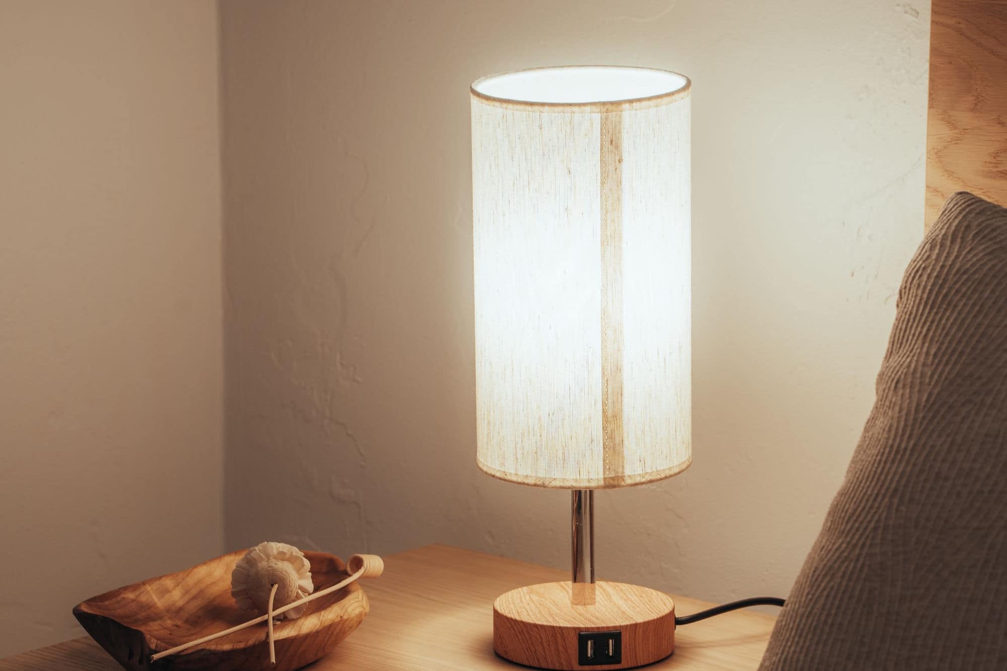 Une lampe de chevet allumée près d'un lit